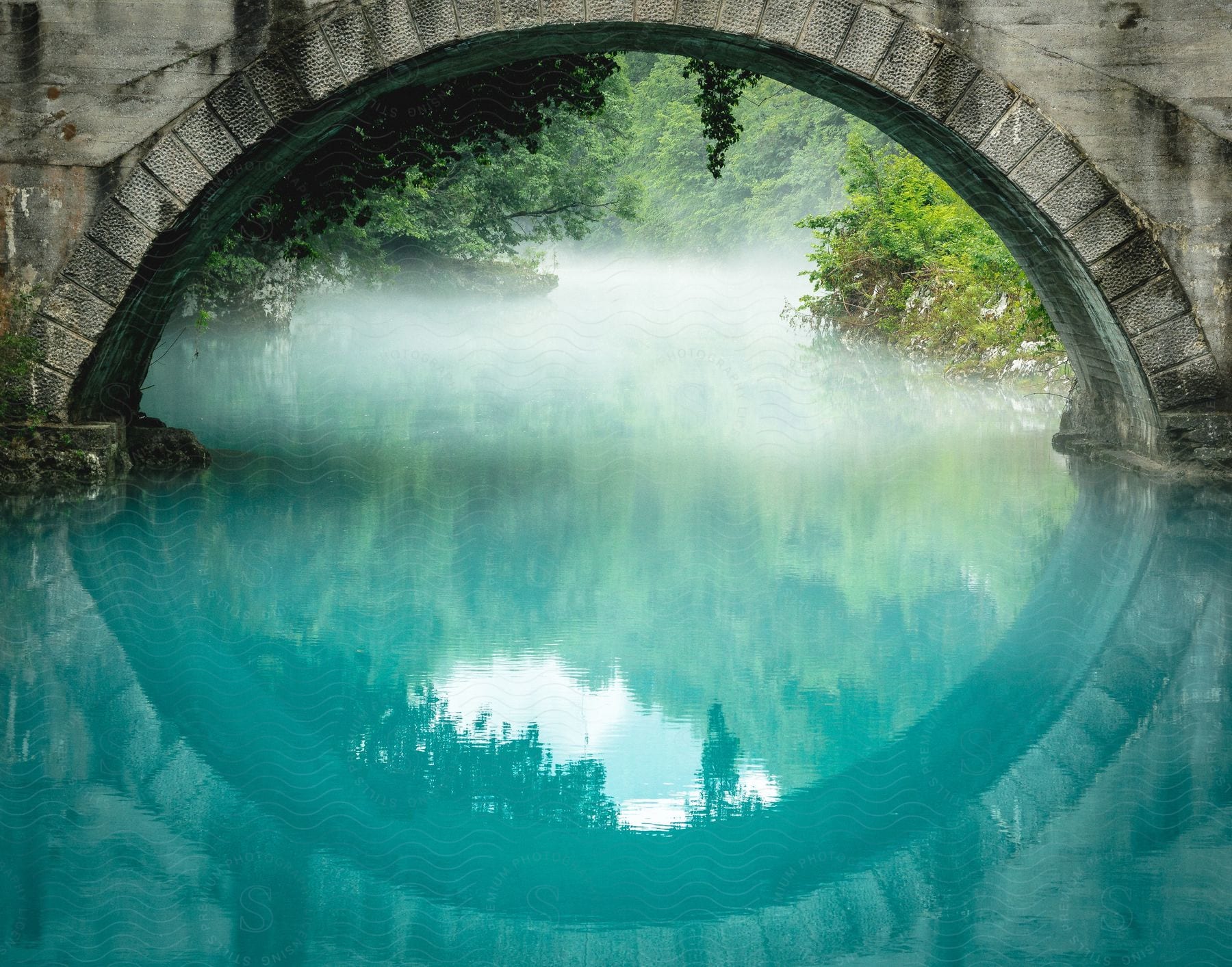 An old stone bridge over a bright blue river