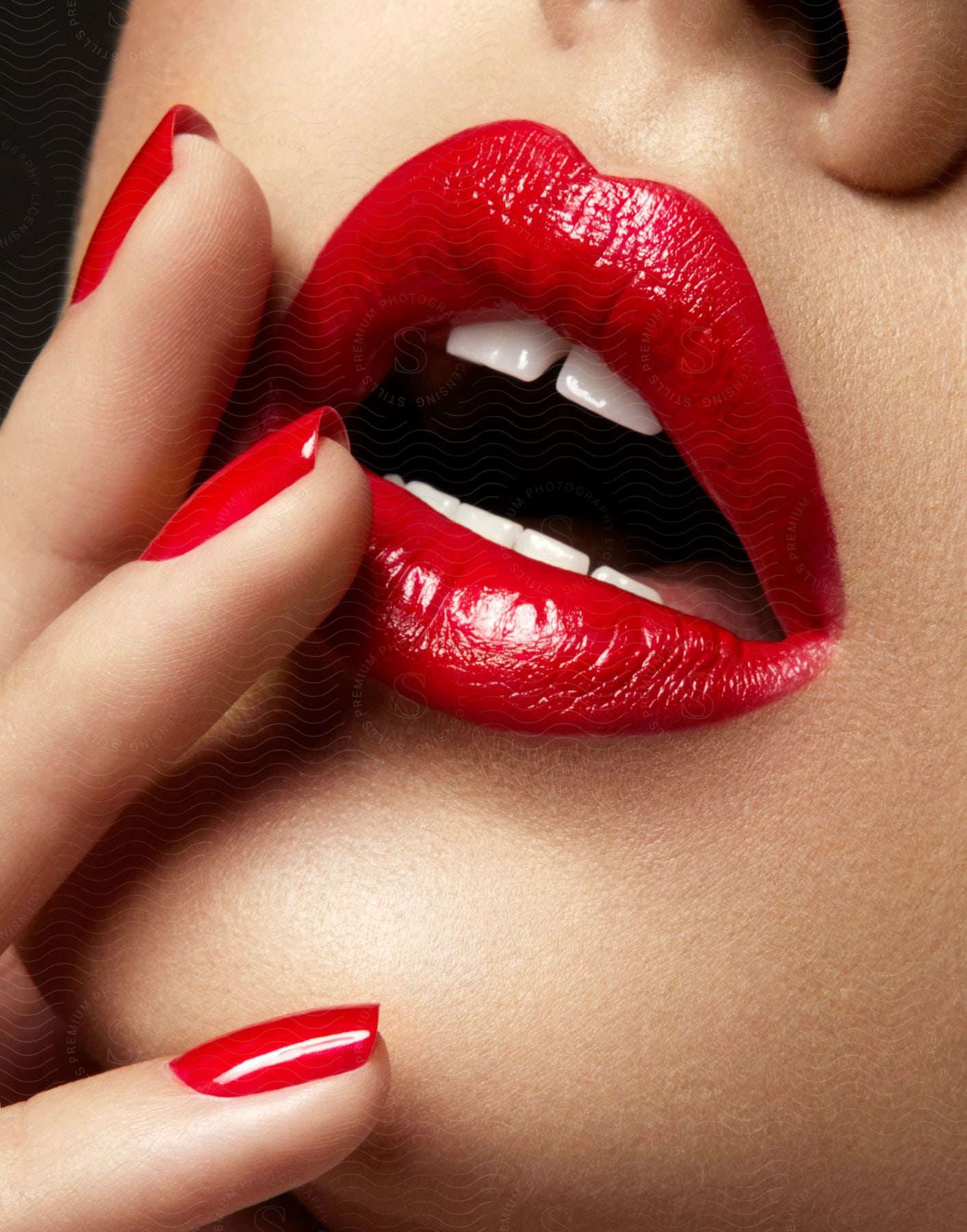 A models mouth touching her lips with nail varnish and red lipstick