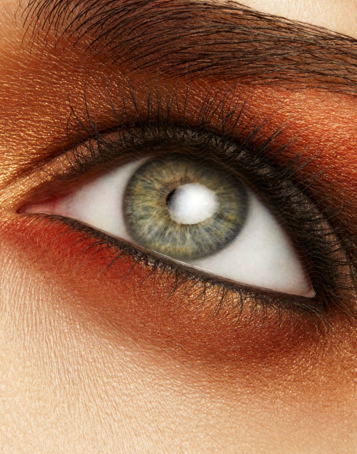 A womans eye with makeup and a white light reflected in the iris