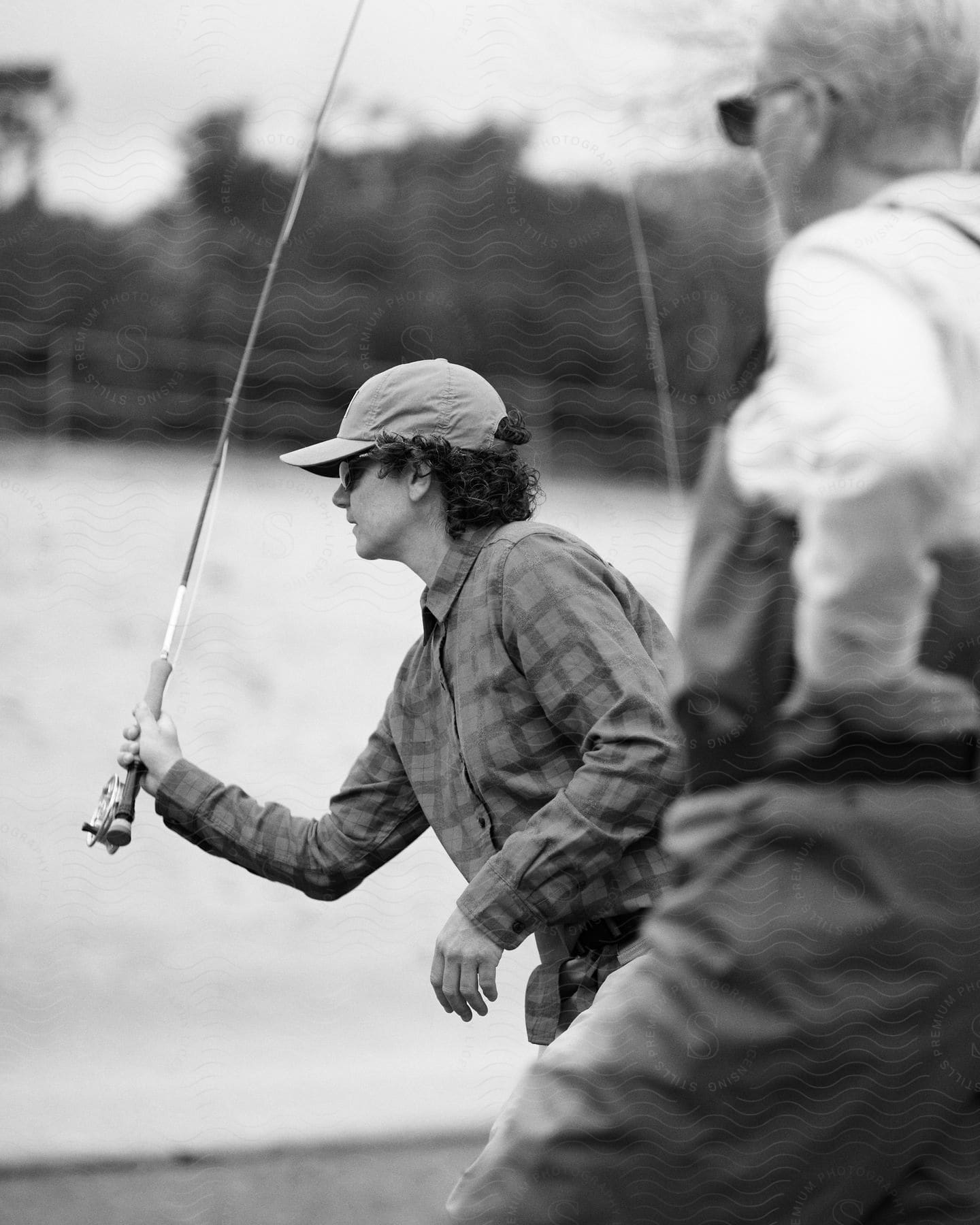 Two men wearing sunglasses are fishing next to water