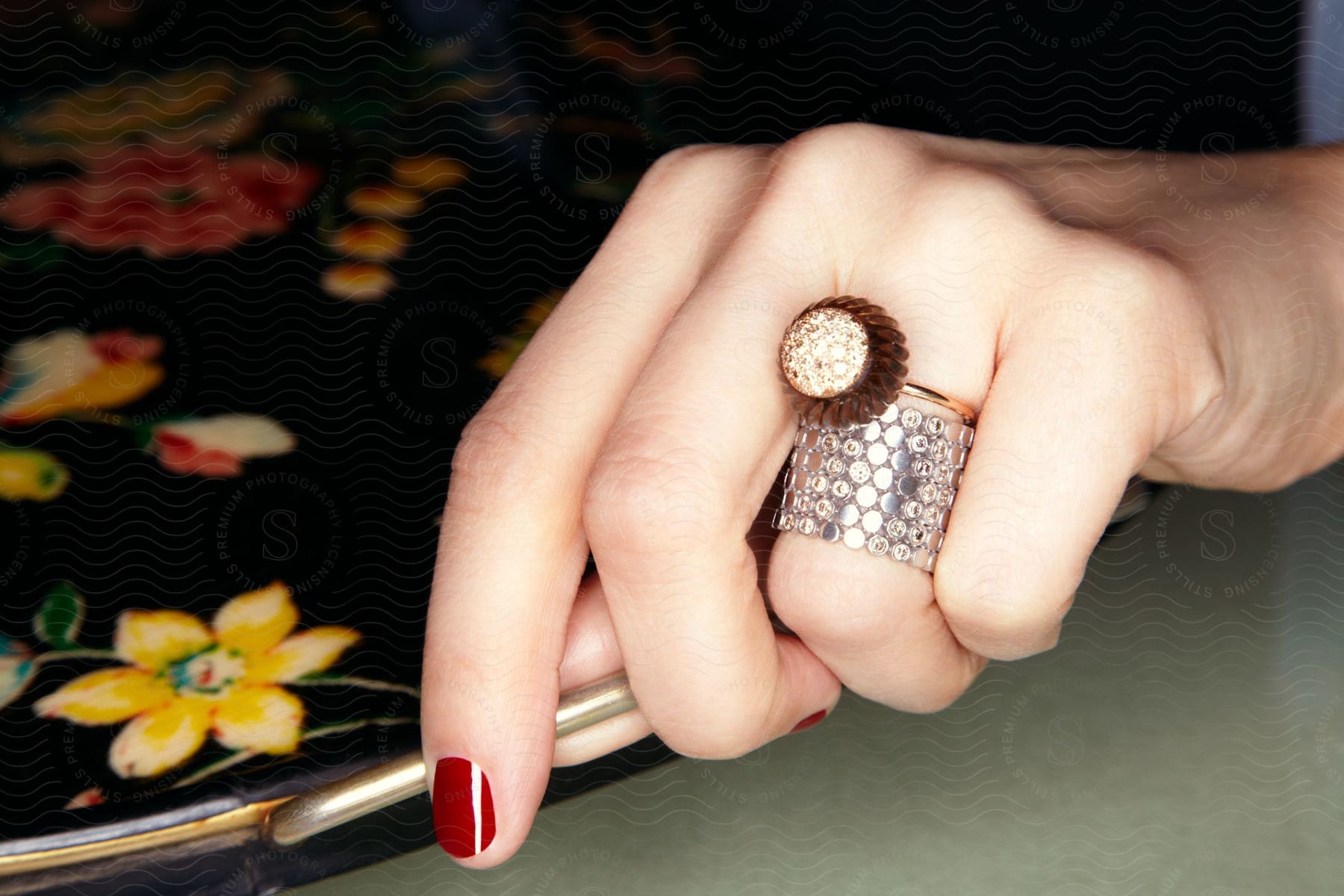 A Woman Holds A Tray With Flower Patterns While Wearing A Flower Ring On Her Finger