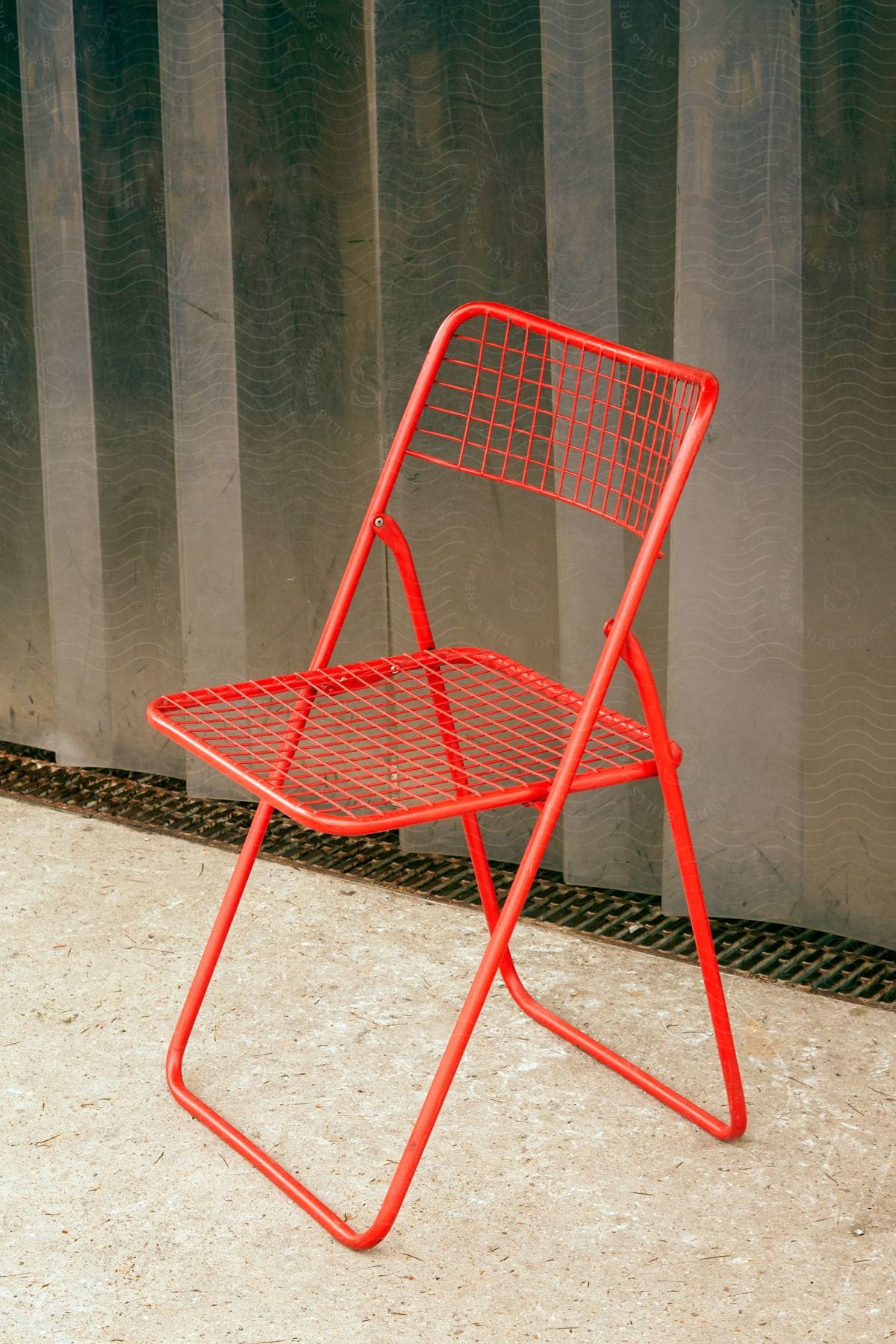 A red chair is placed on the floor near a room divider wall