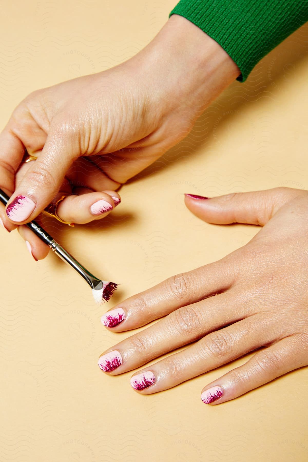 A woman is seen painting her nails with a brush