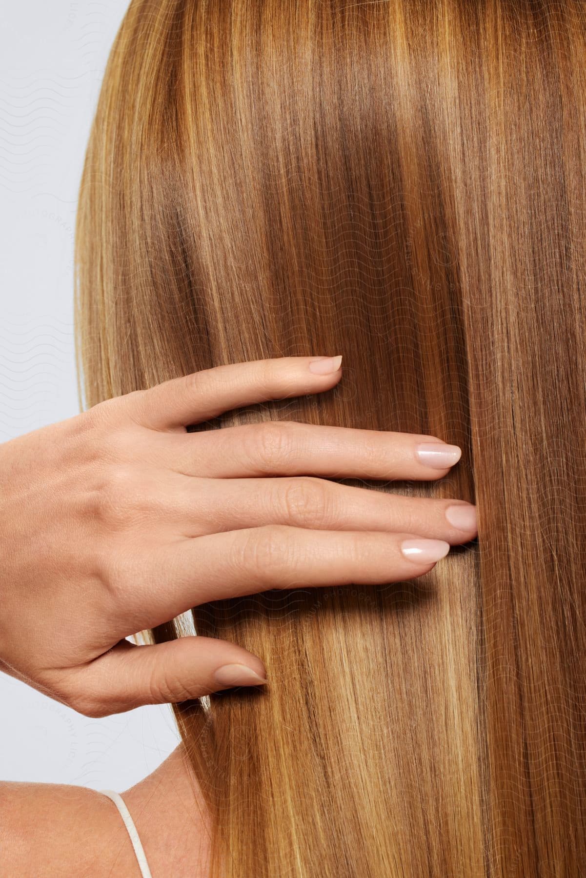 A woman with red hair holds her painted fingernails in front of her hair