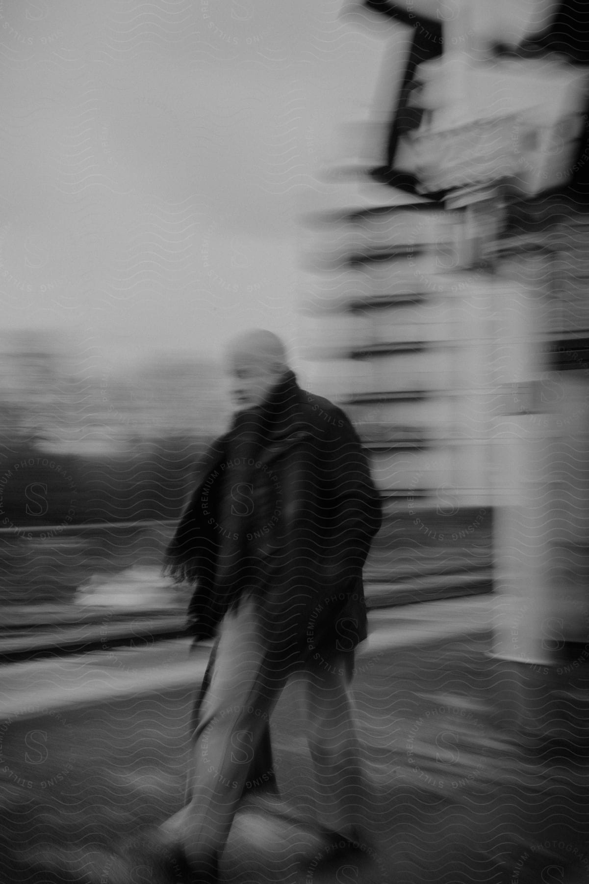 A man walking down a street in a blurred black and white photo