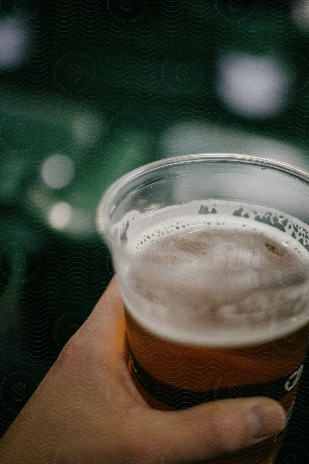 A hand holding a cup filled with beer