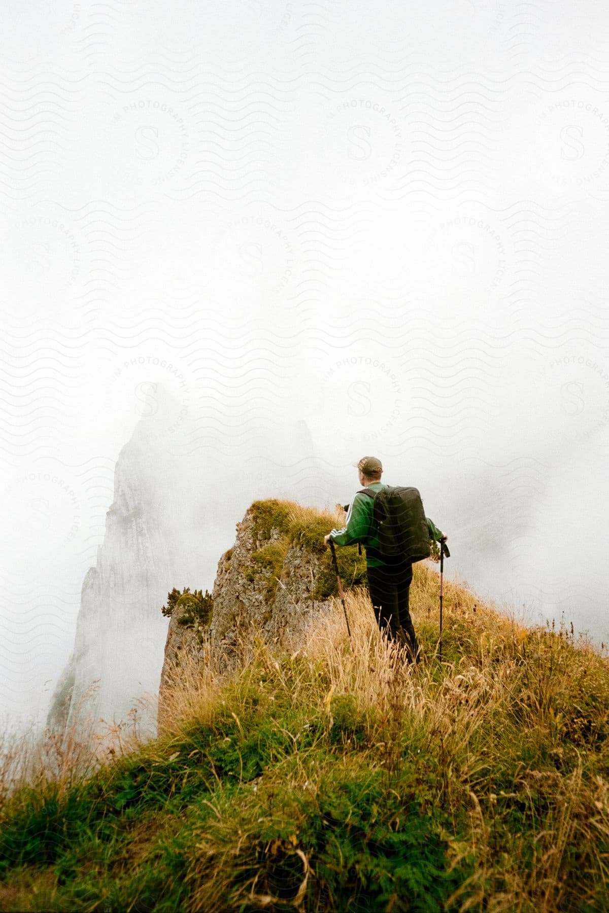 A person hikes up a mountain with hiking poles and a backpack