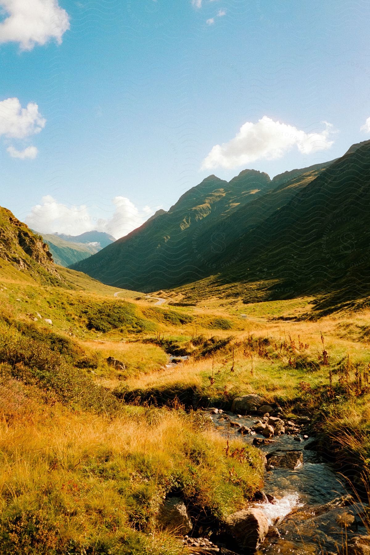 A Stream Runs Through A Valley With Mountains On Both Sides