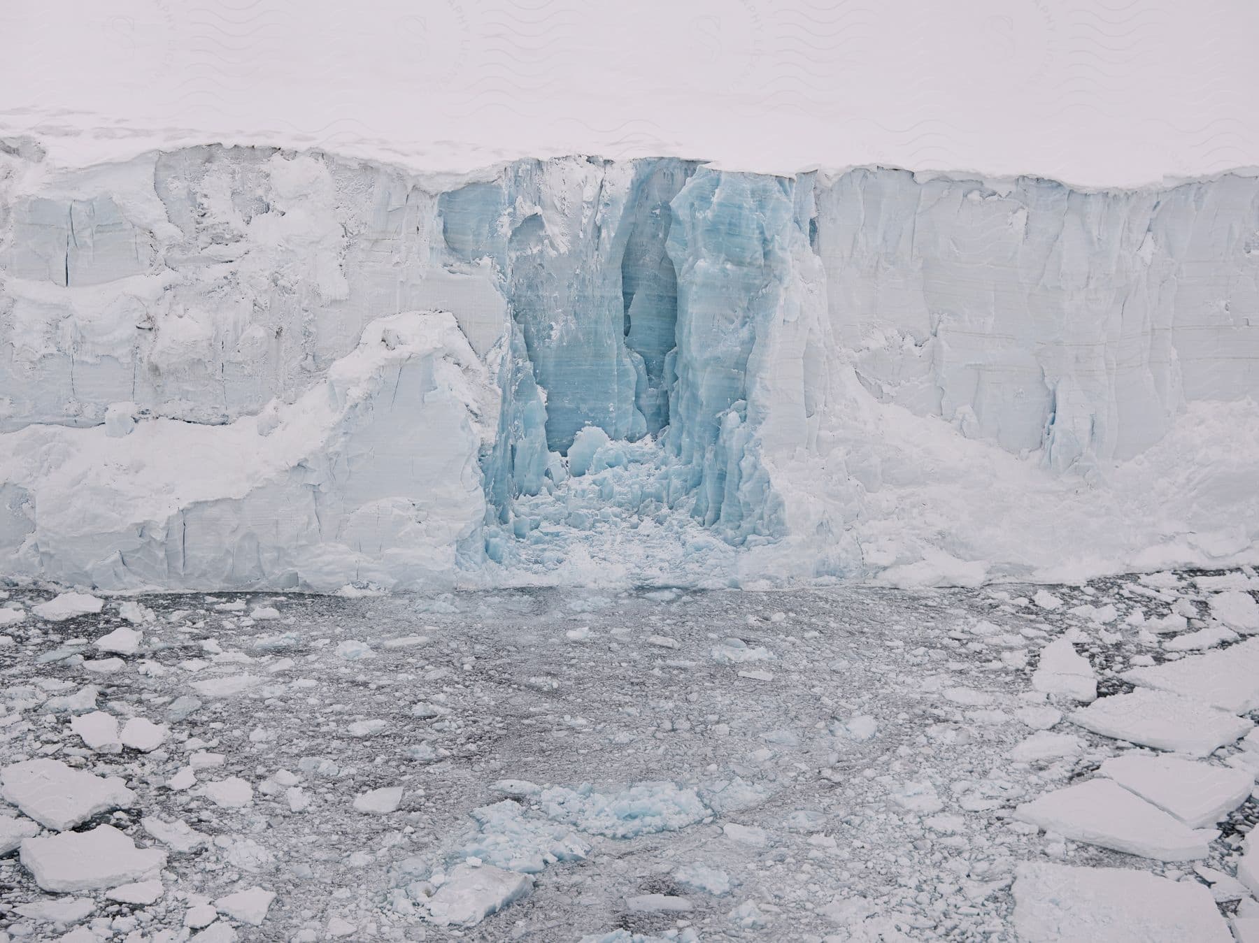 A frozen mountain landscape with a clear sky and a body of water