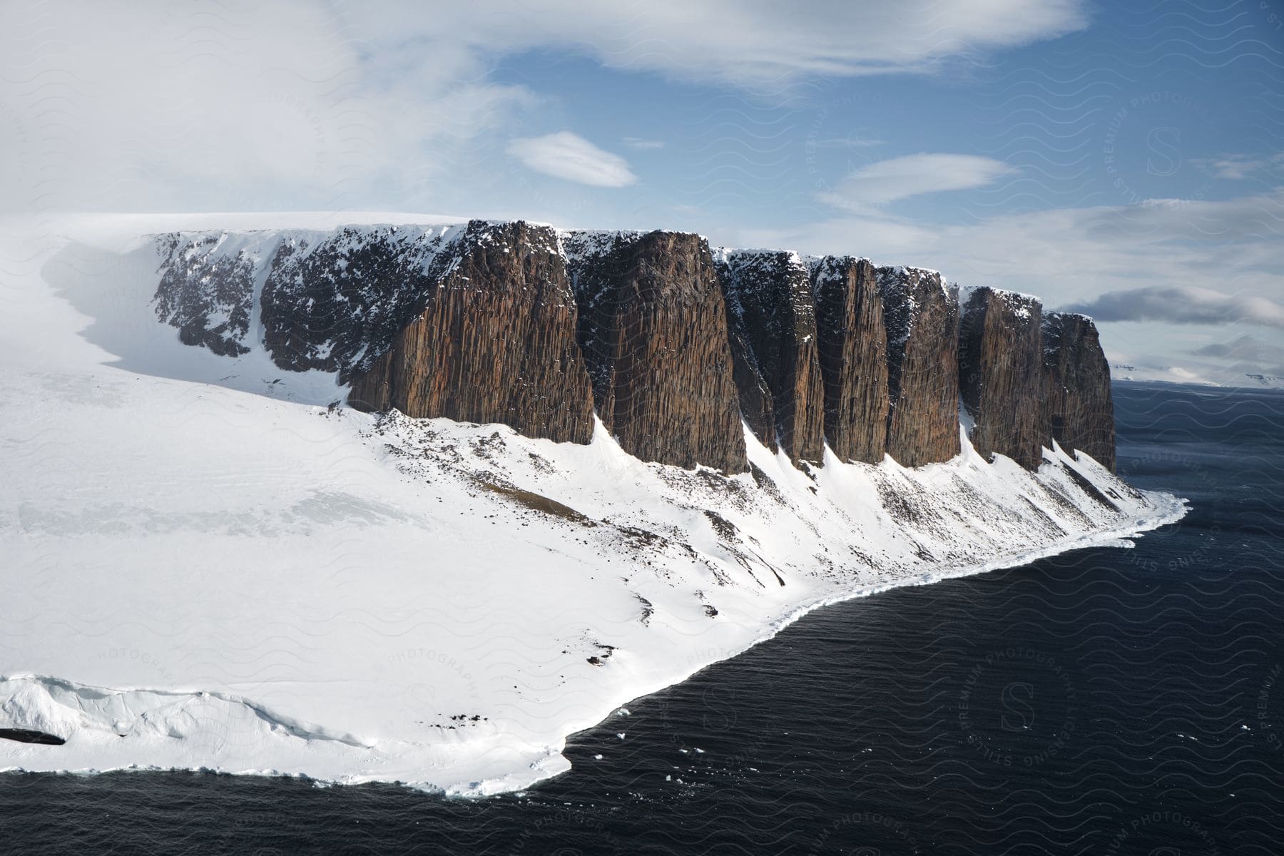 A lake near snow rocky formations under a cloudy sky