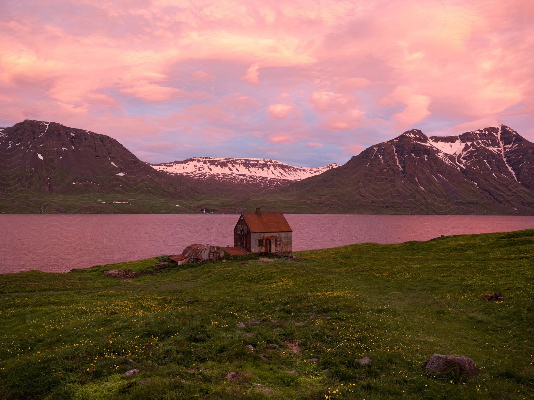 A serene countryside scene with a lake mountains and a small hut