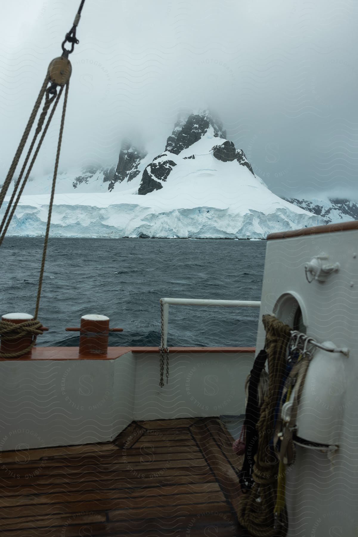 A snowy bank rises to a mountain seen from the deck of a boat