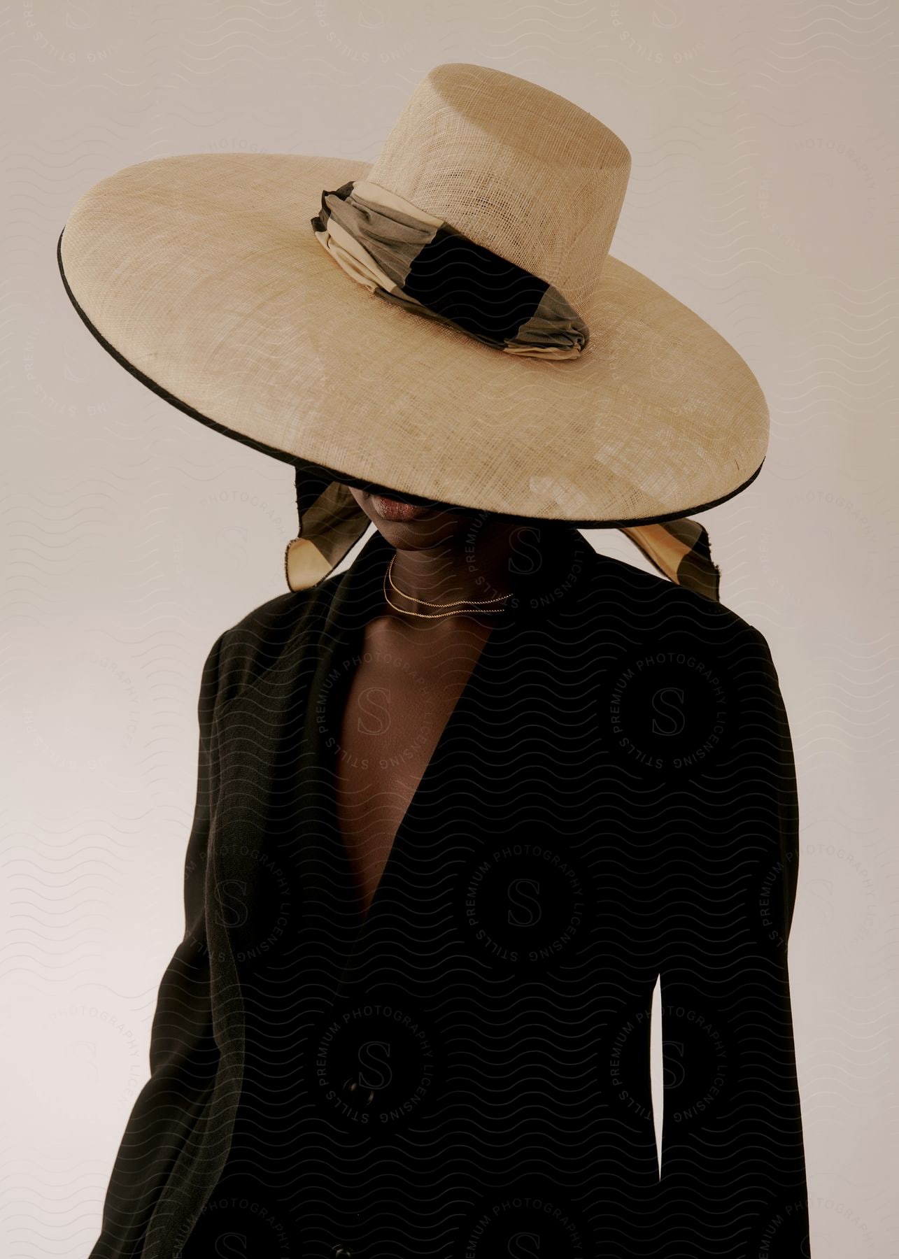 A black woman dressed in black wearing a hat that covers most of her face