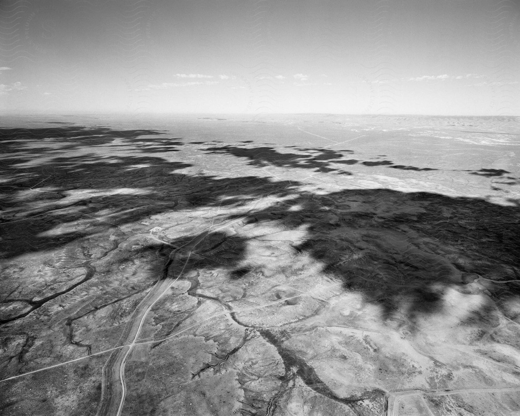 A black and white photo of a barren landscape with tire marks