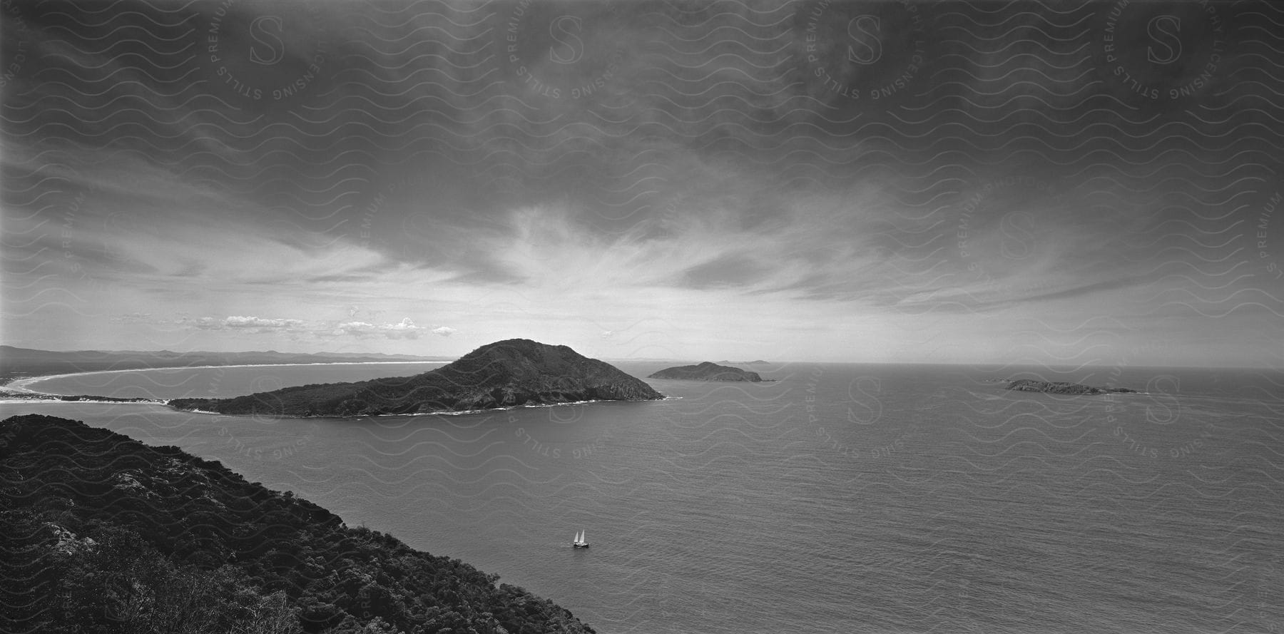 A blackandwhite aerial view of a coastal shoreline with cloudy skies