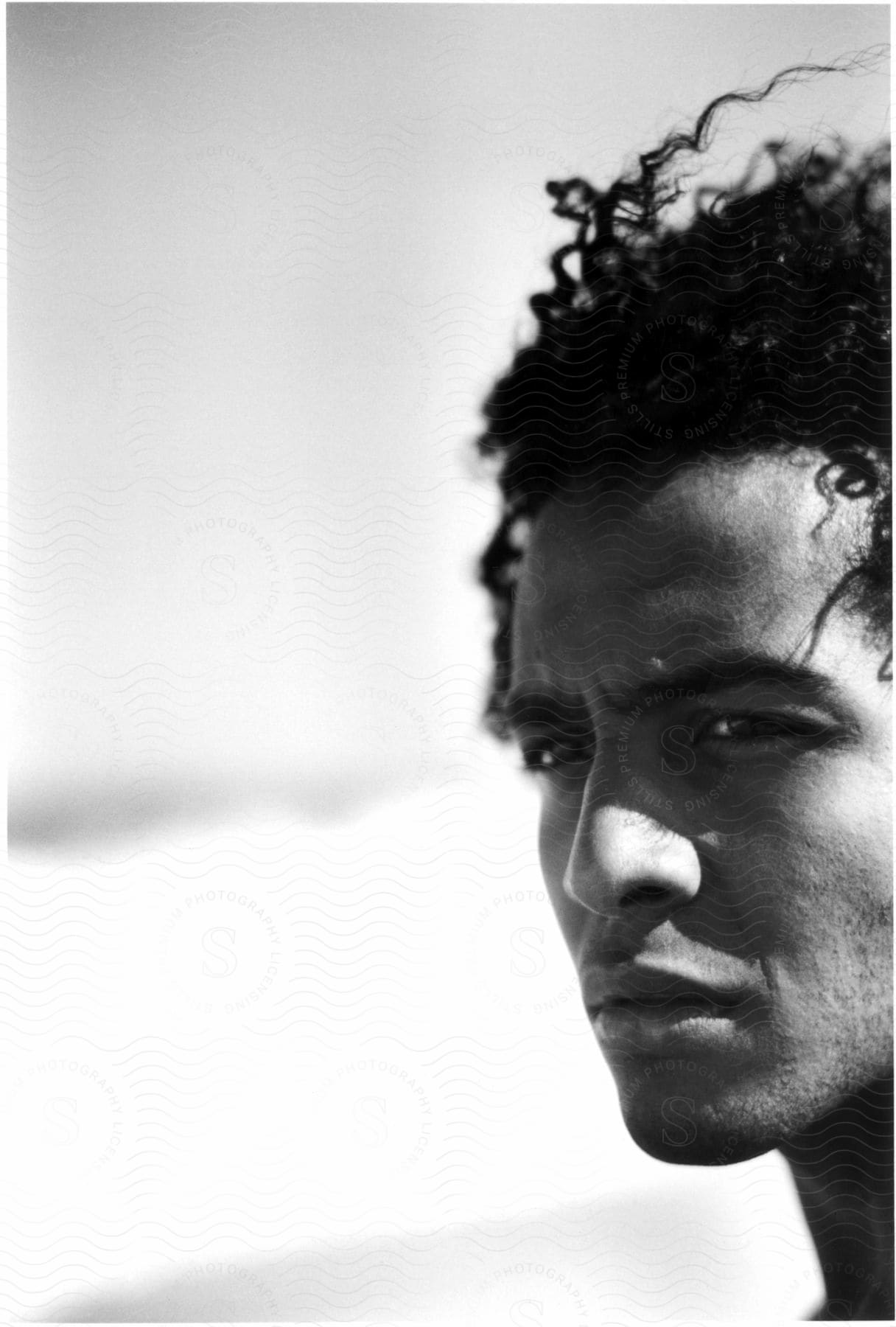 Closeup of a mans face with curly hair looking left