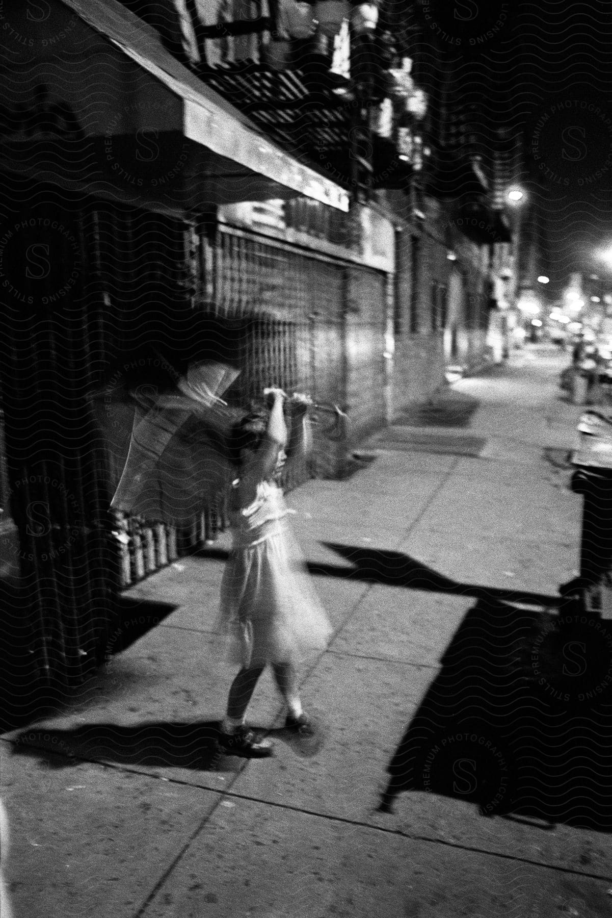 A girl holding an umbrella while standing on a walkway at night