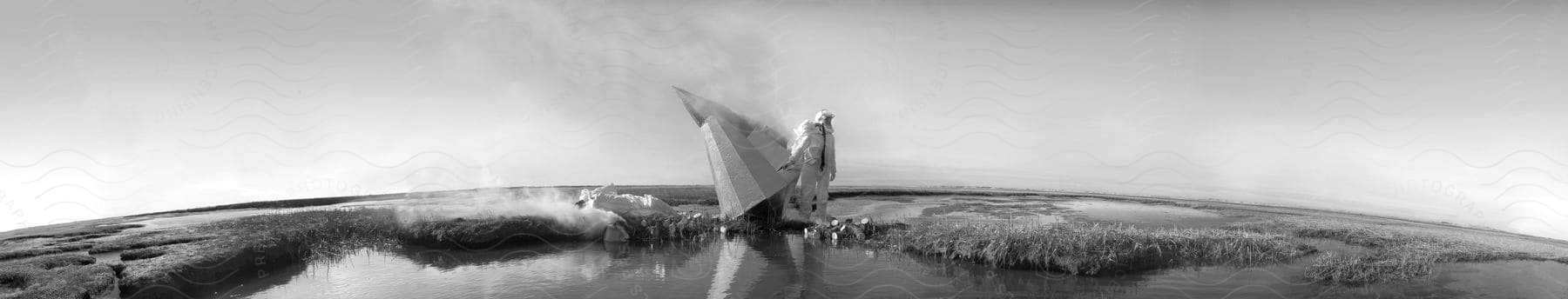 A crowd gathers around a smoldering rocket along a lake