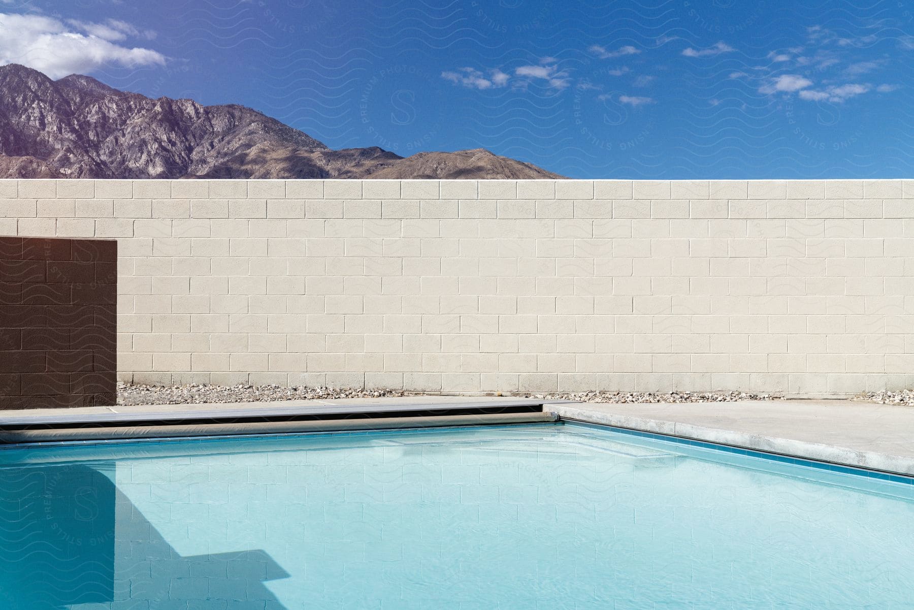 A pool next to a white wall in a backyard