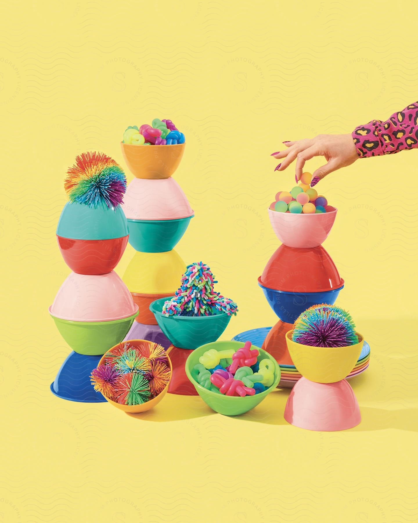 Many colored containers with colored objects inside one hand takes a spherical candy yellow background