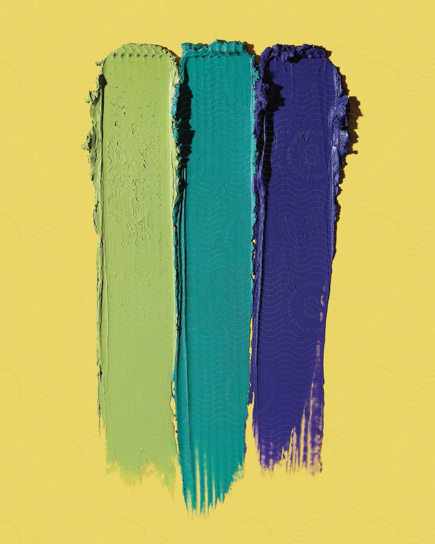 Different types of paint colors placed on a yellow surface