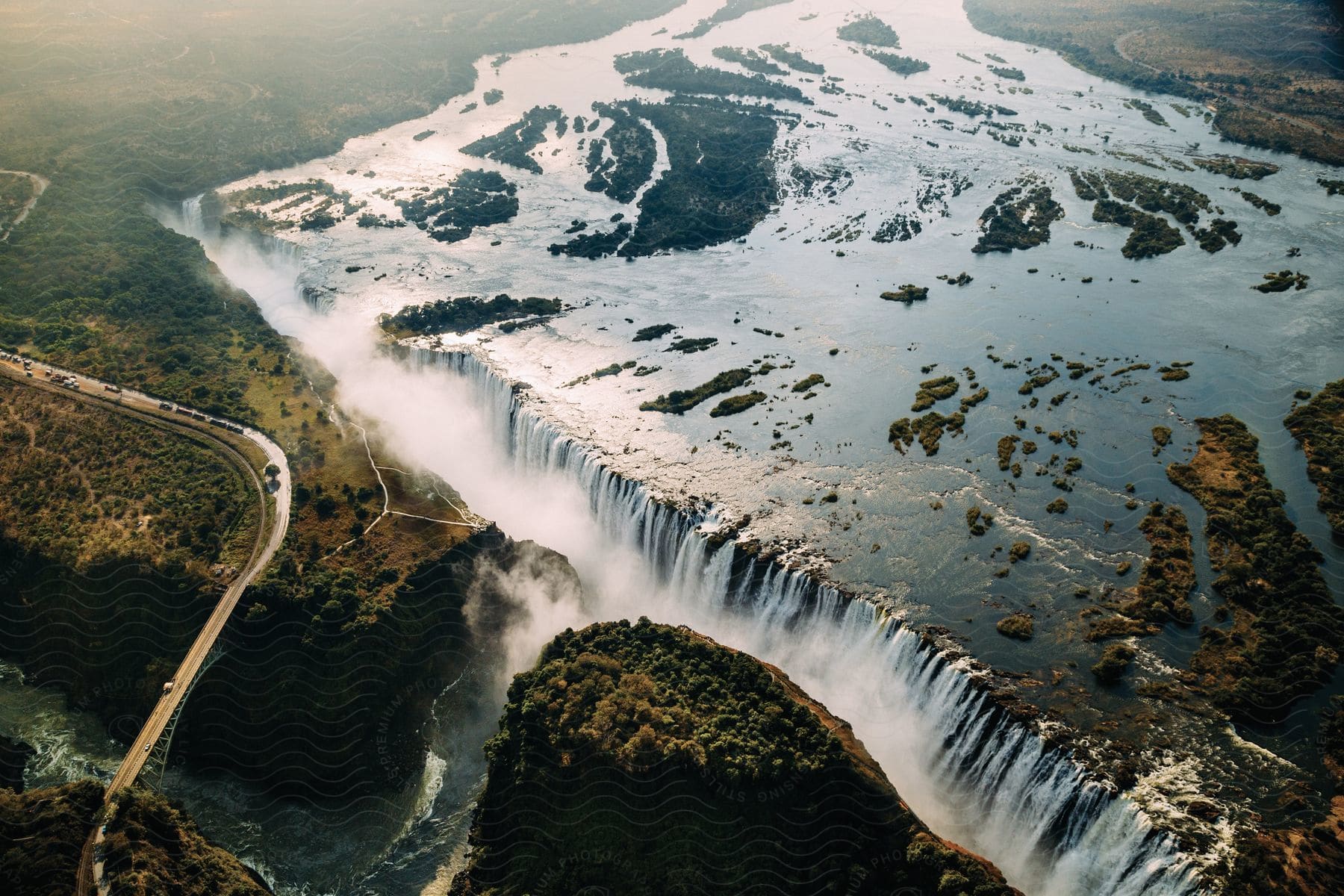 A cascading waterfall winding road bridge and river are visible from above