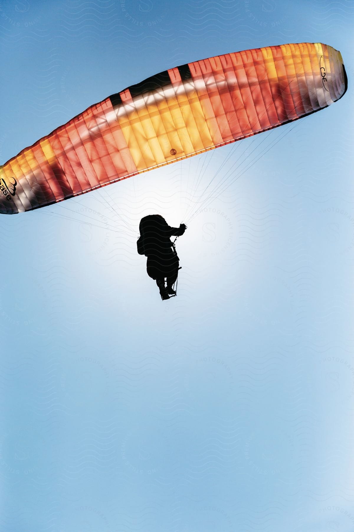 A person on a parachute in the sunny sky