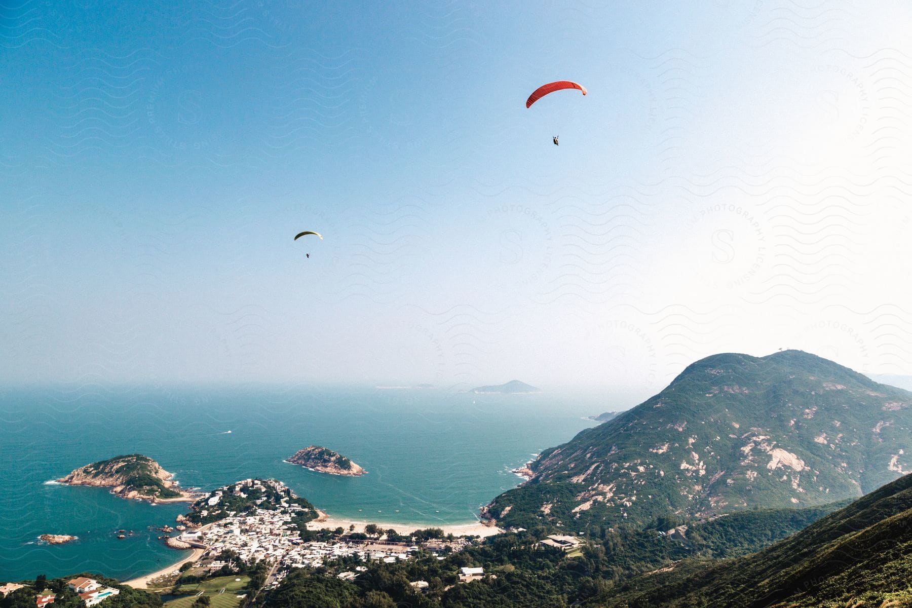 Two people paragliding over a mountain and sea