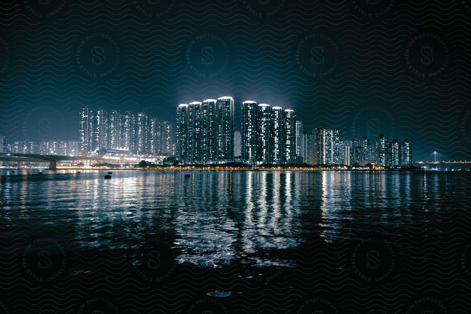 A bright city at night with many skyscrapers is seen over the water