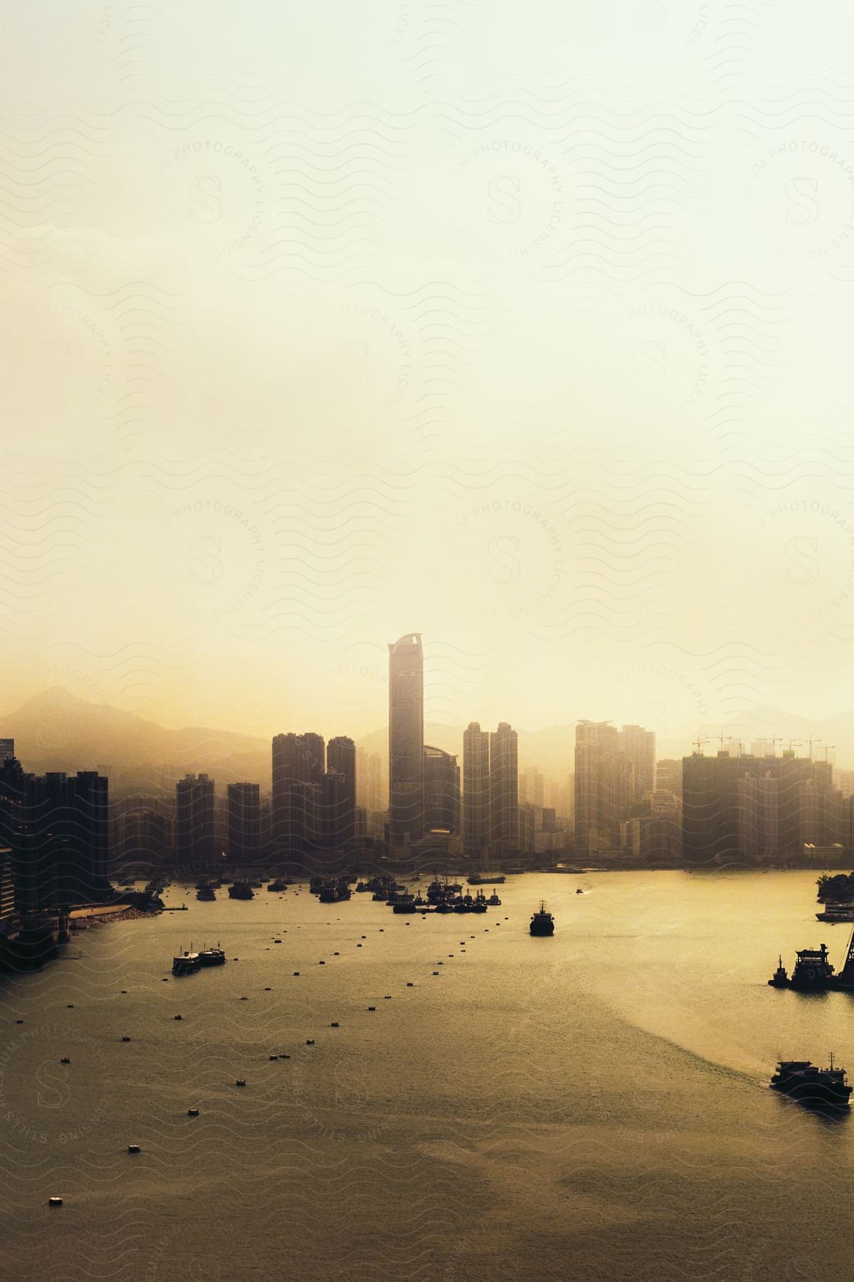 A cityscape and water at sunset silhouetted against a yellow sky with boats in the water