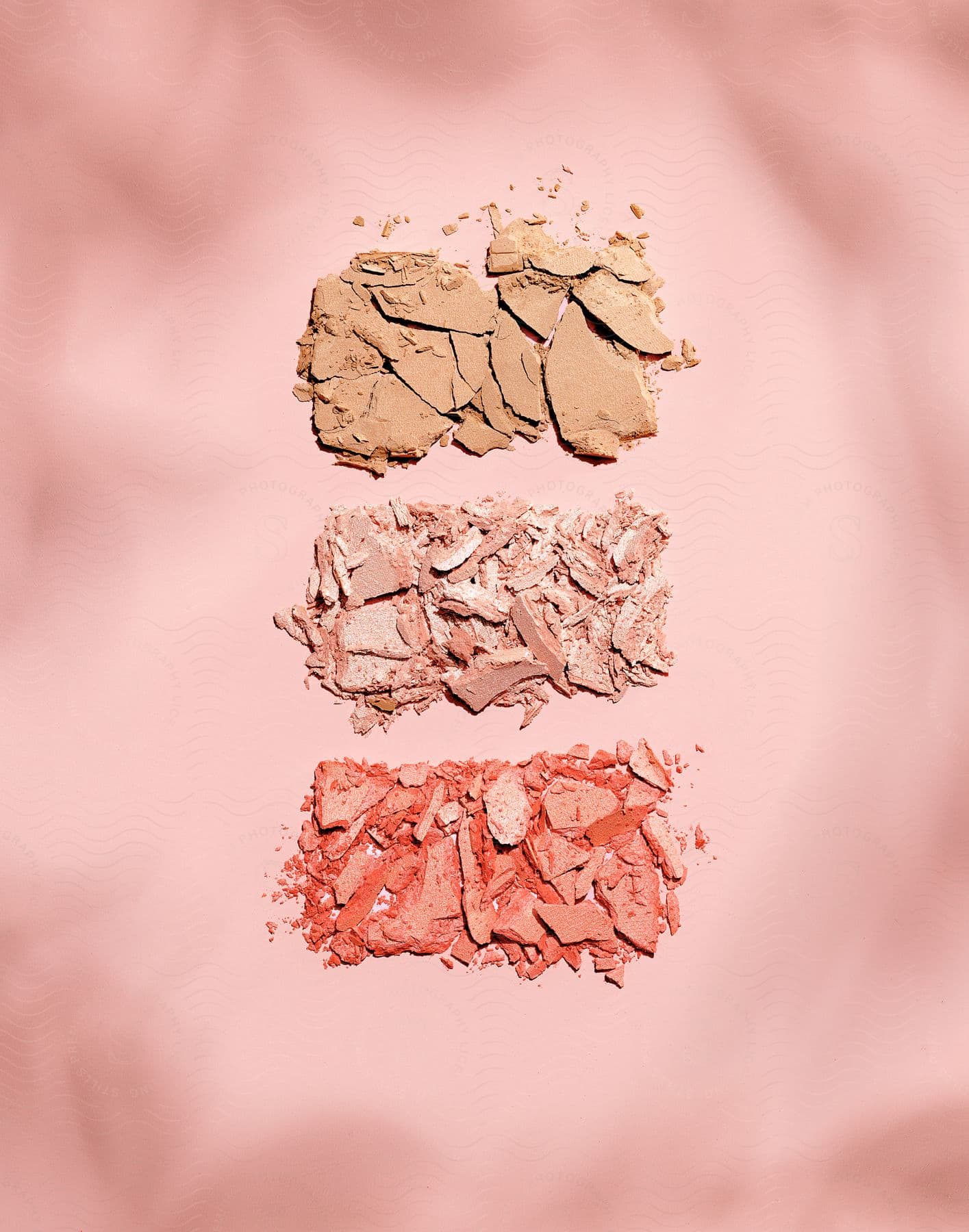 Three groups of tan pink and orange powder stacked in a block format against a pink background