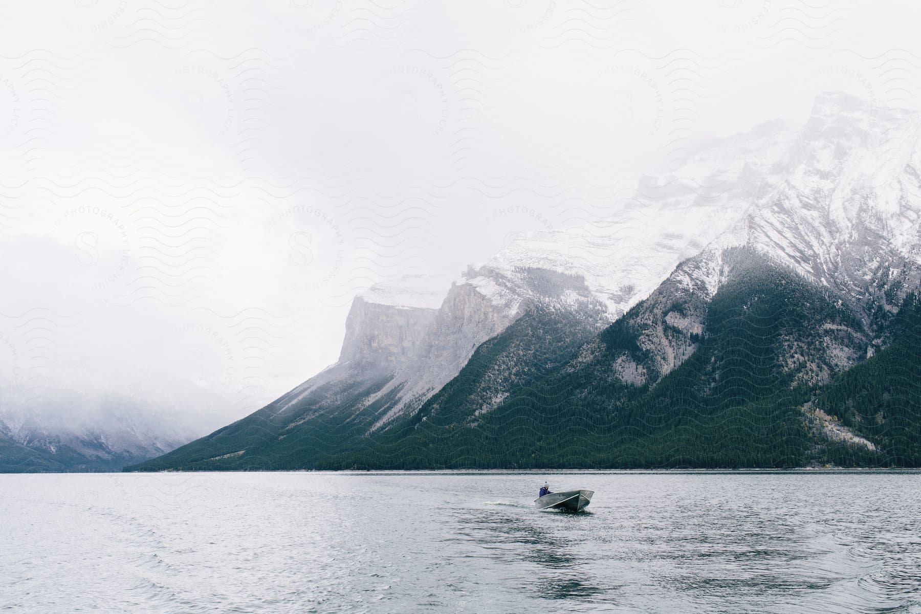 A serene mountain landscape with a lake boat and snowy peaks