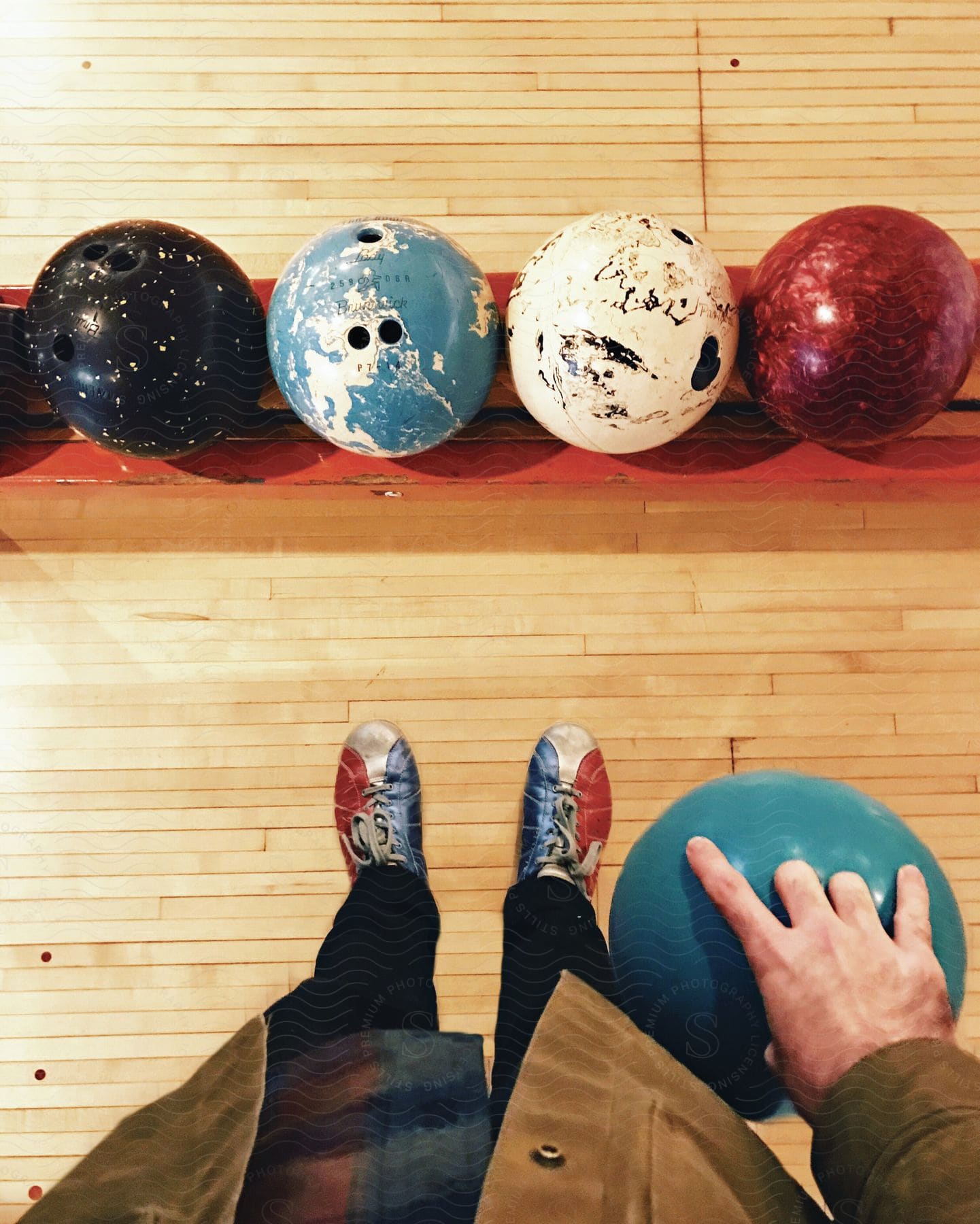 Man wearing jacket pants and bowling shoes holding a bowling ball with four others in front