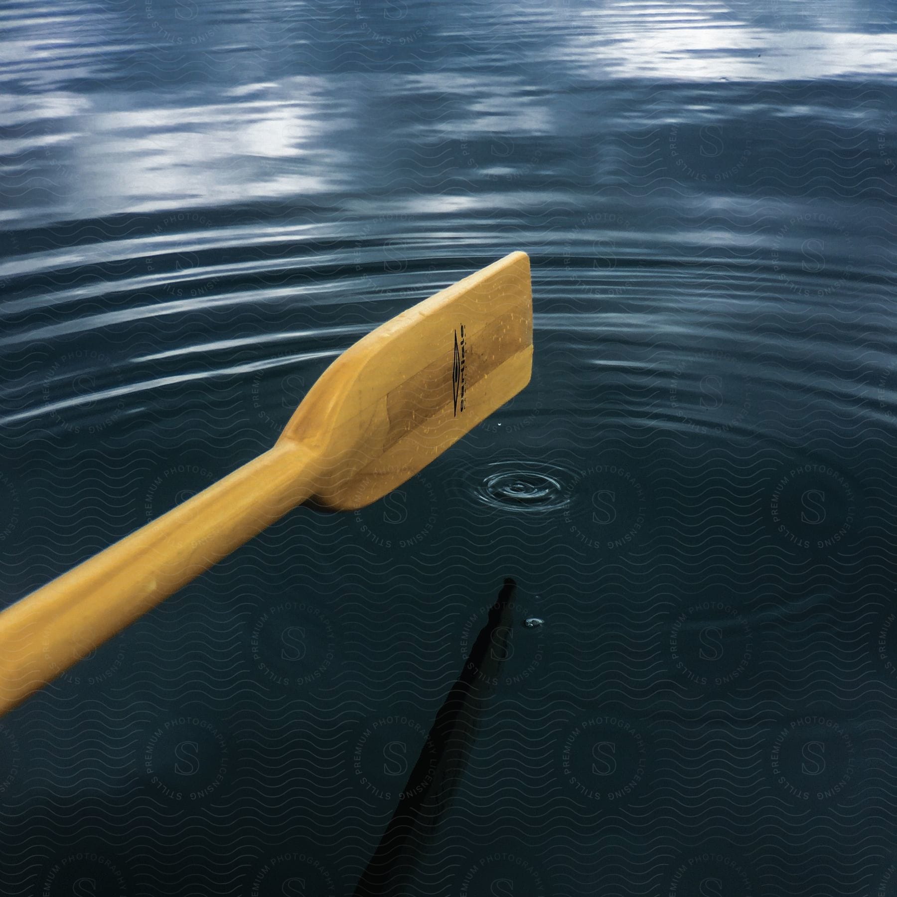 A canoe floating on a lake with sunlight reflecting off the water ripples