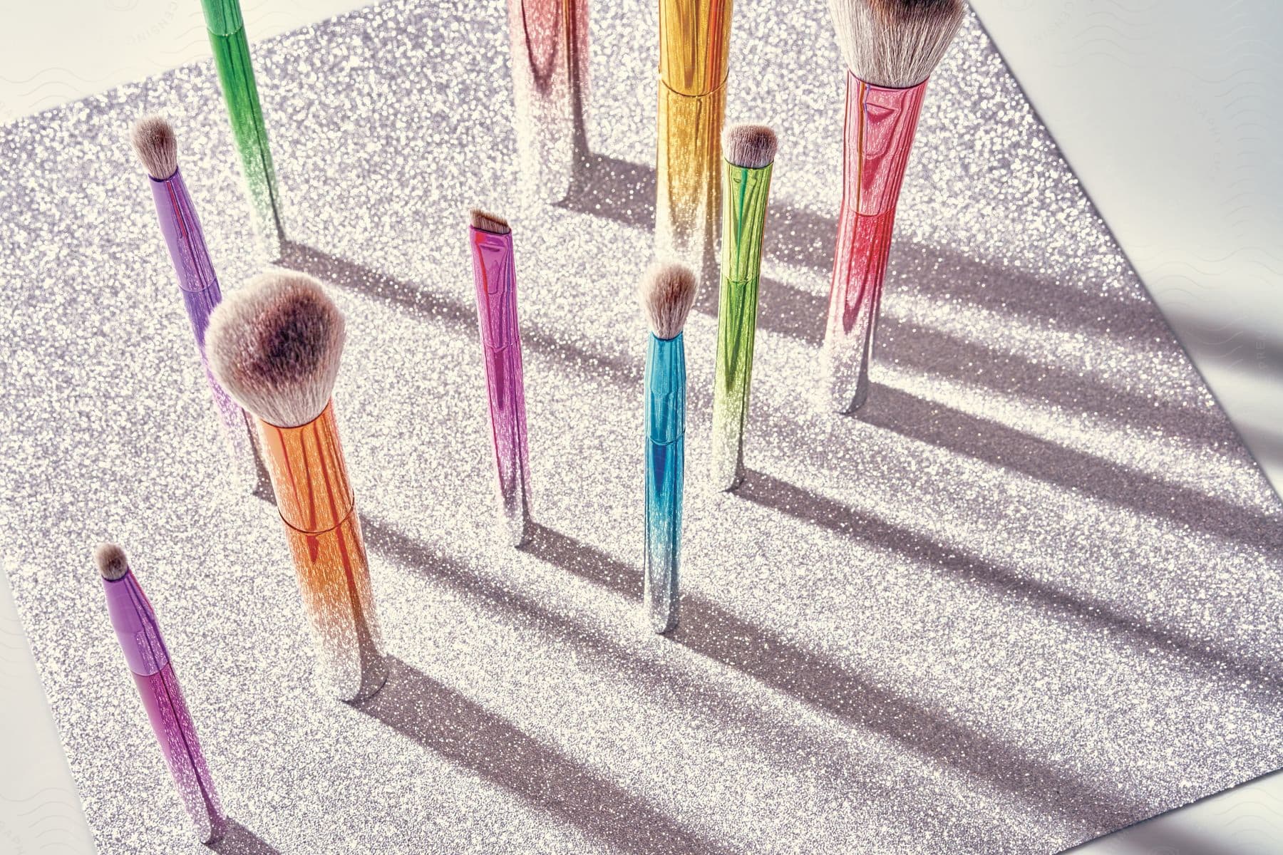 Makeup brushes standing up on a row over a shiny surface