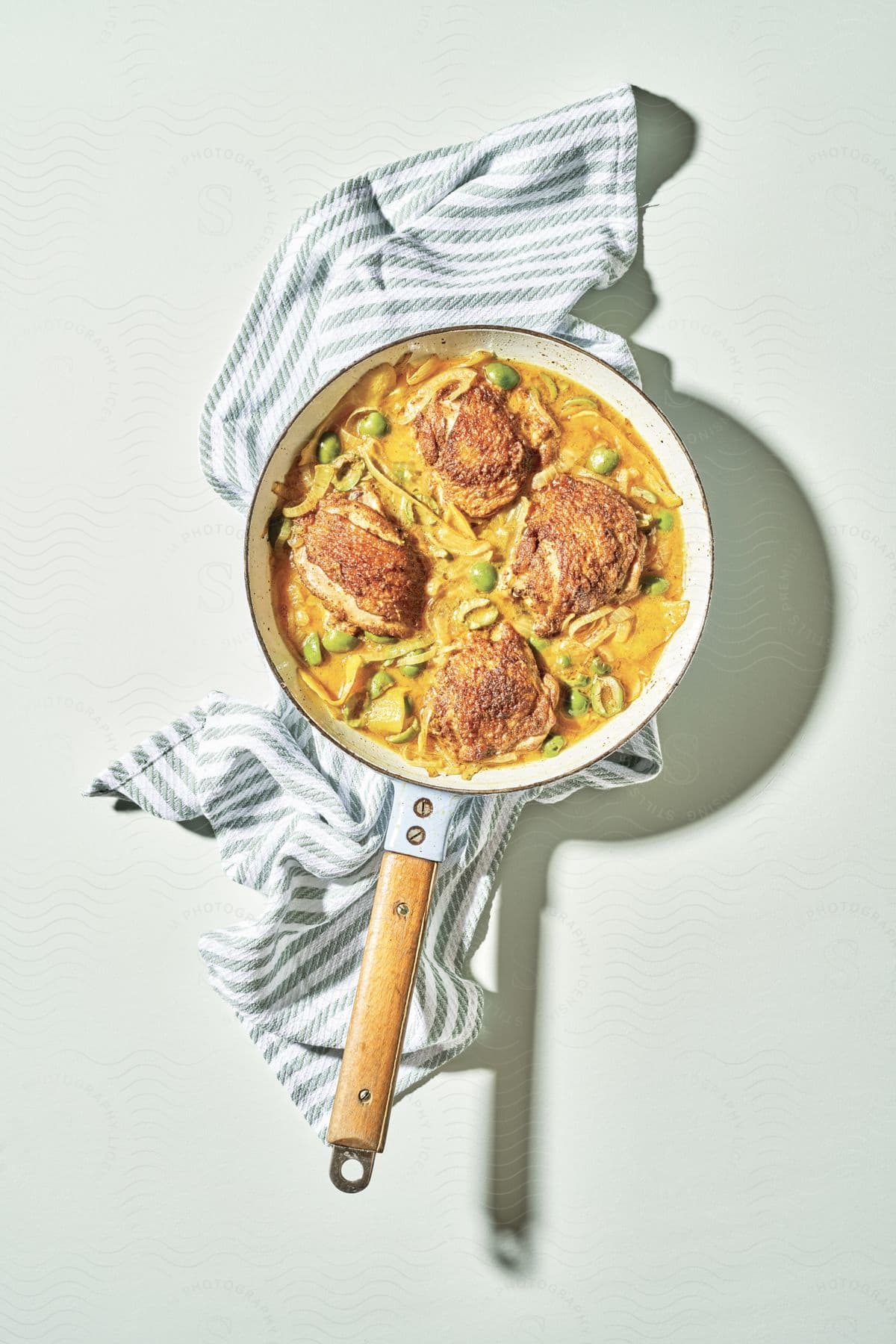 A pot of chicken noodles sitting on a dish towel on a counter