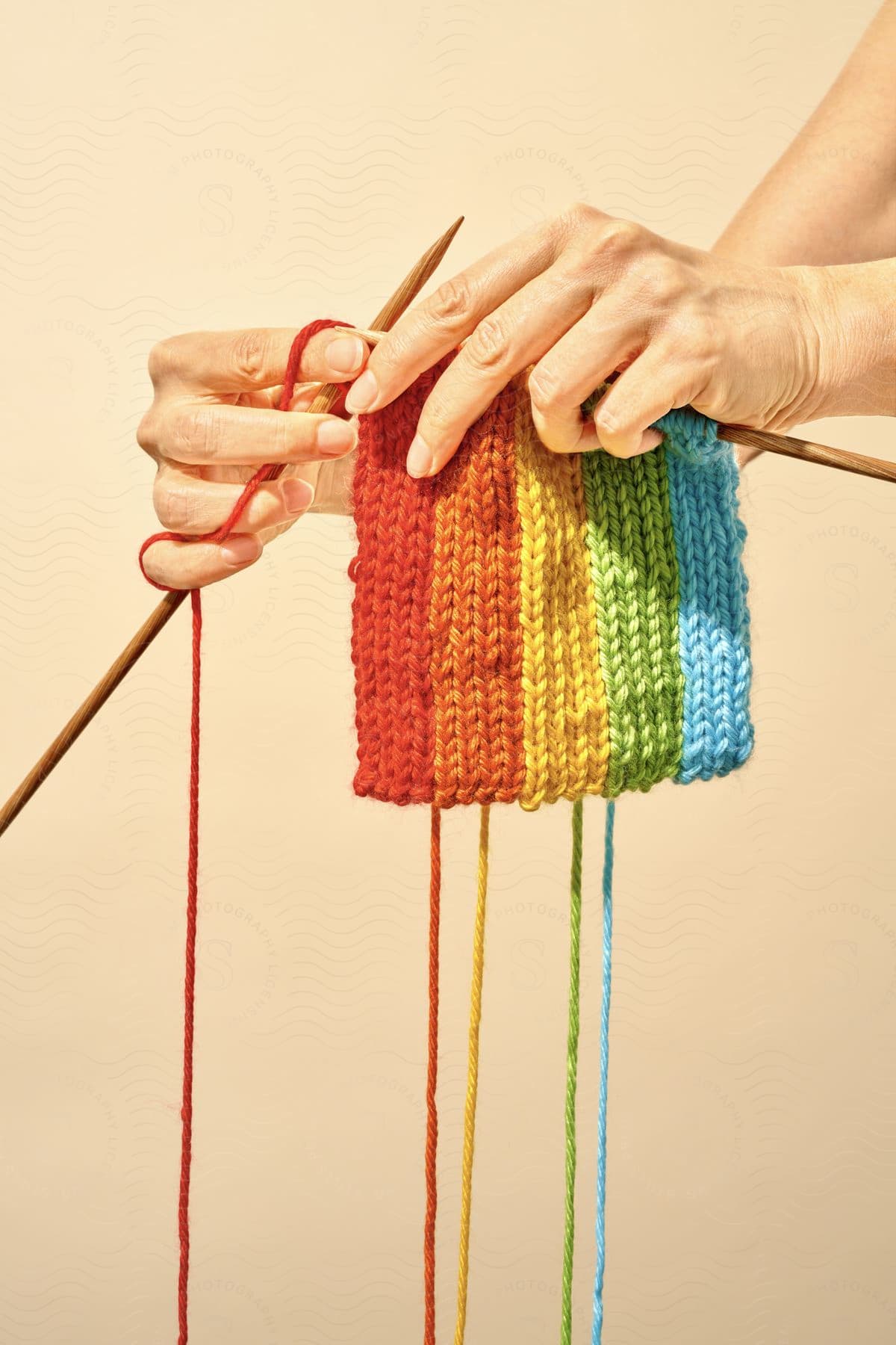 A person knitting with two sticks and wool