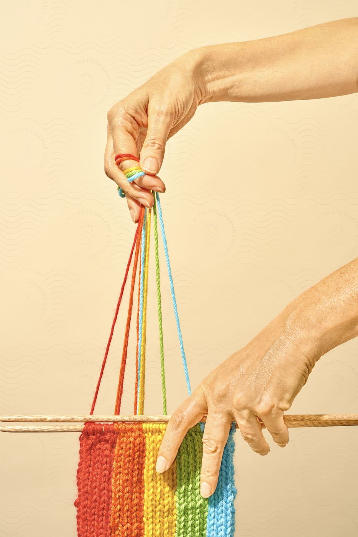 A person holding a rainbowcolored knitting project