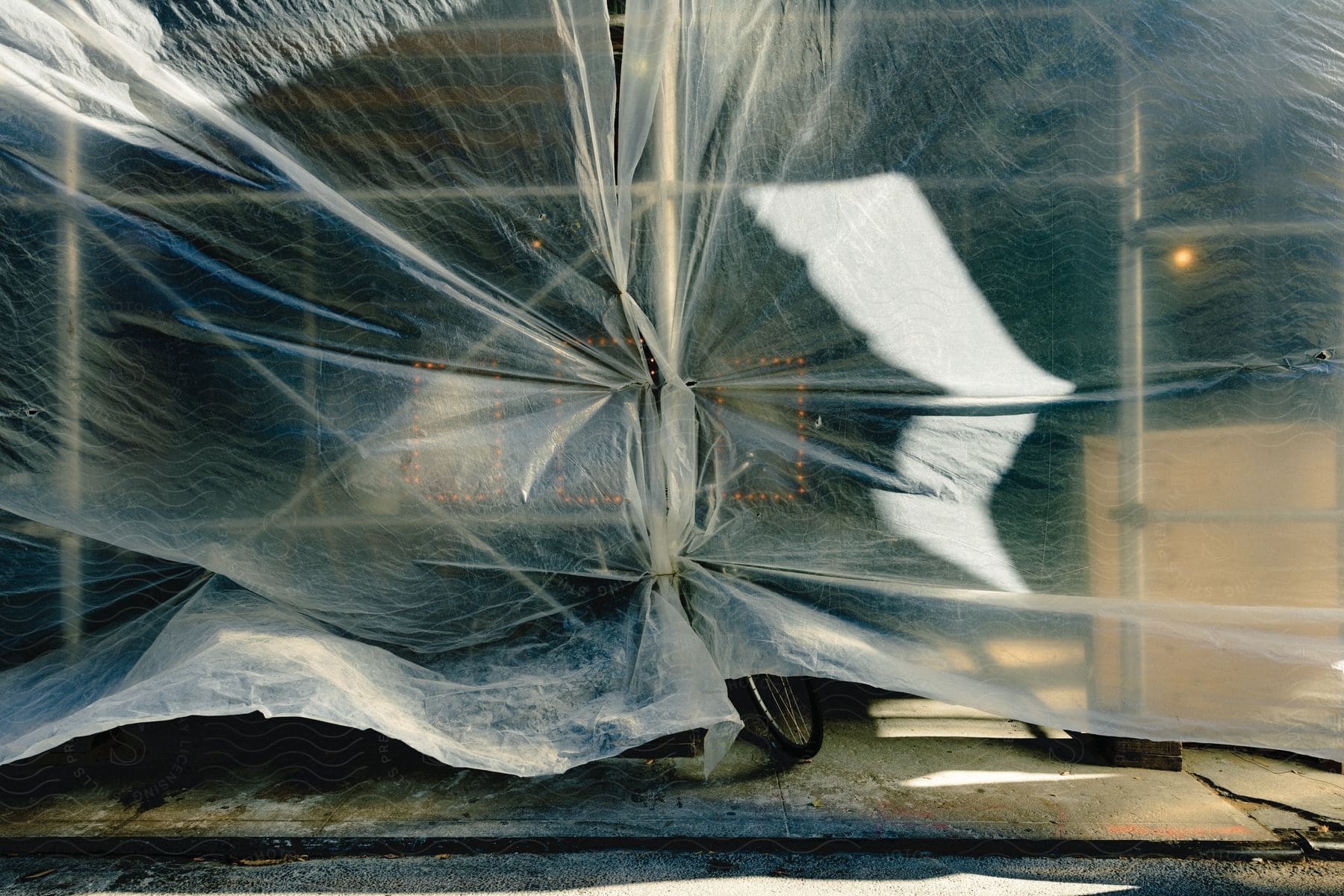 Plastic sheeting covering scaffolding reveals glimpse of bicycle tire