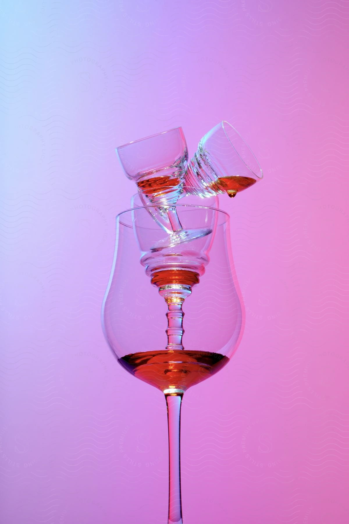 Stock photo of an arrangement of stacked wine glasses with a small amount of red liquid in each glass in a studio environment