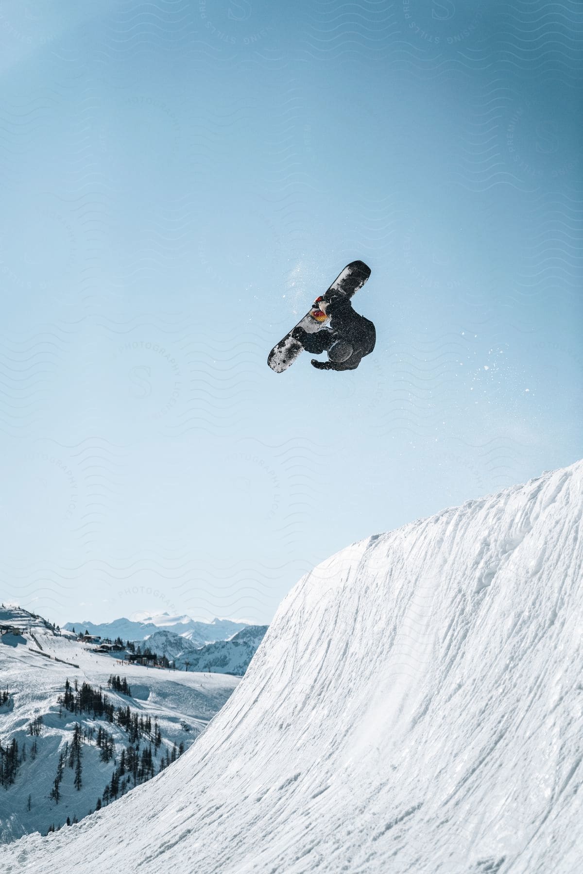 A person snowboarding jumps over a mountain in the austrian alps