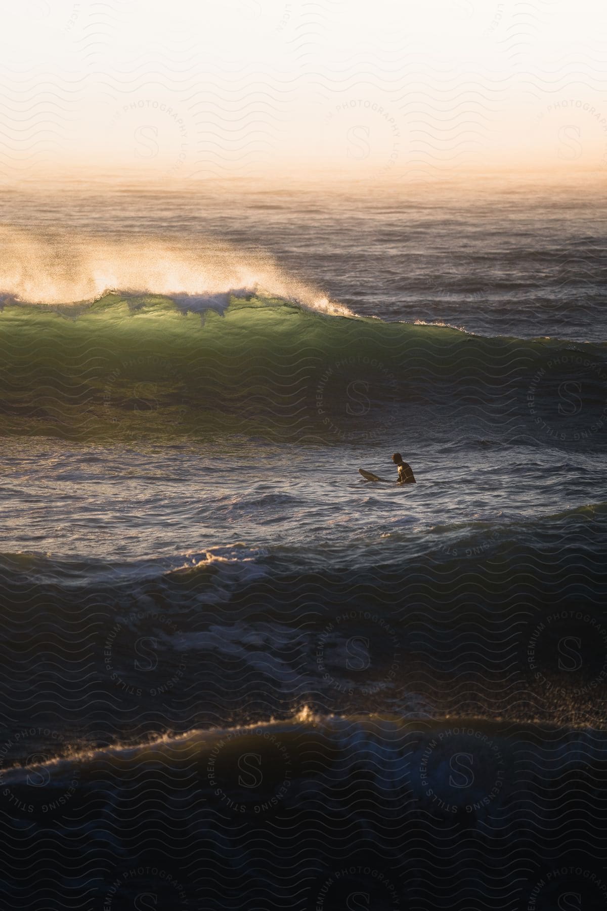 A man is paddling on a surfboard in the wavy sea