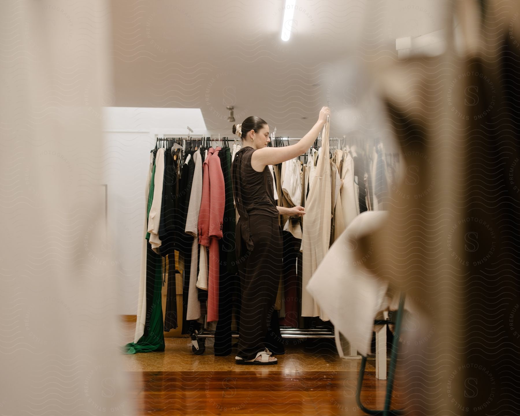 A woman holds up a dress on a clothing rack in a store