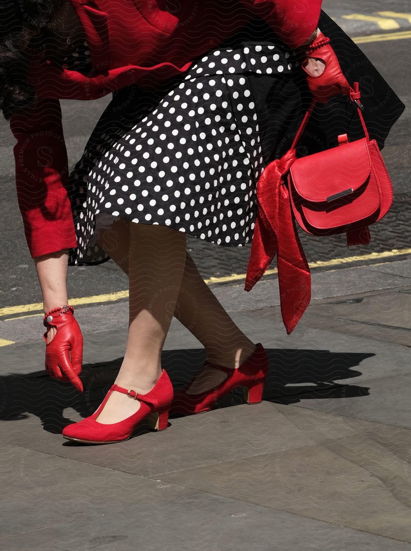 A woman walking on a city street wearing a vintage dress and accessories