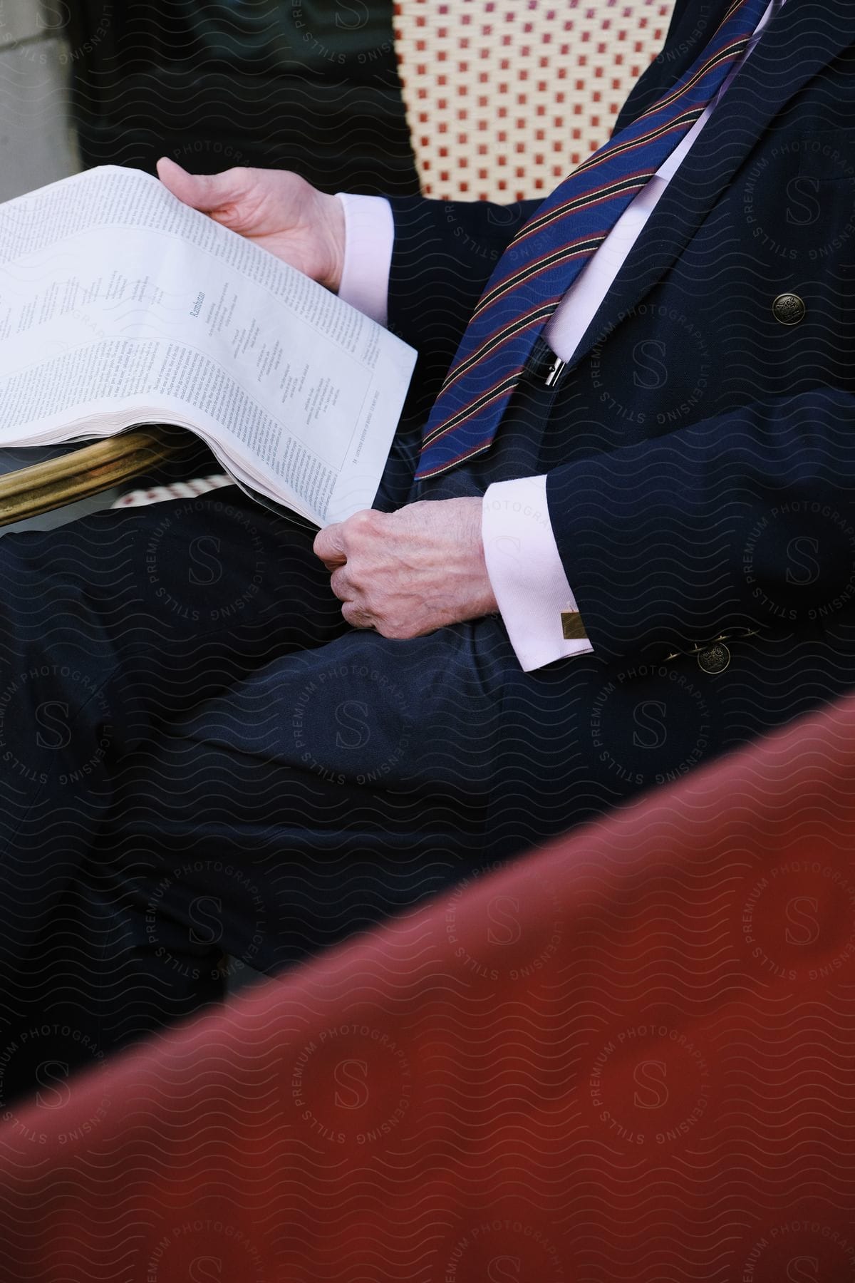 A man is sitting on a chair and reading a paper