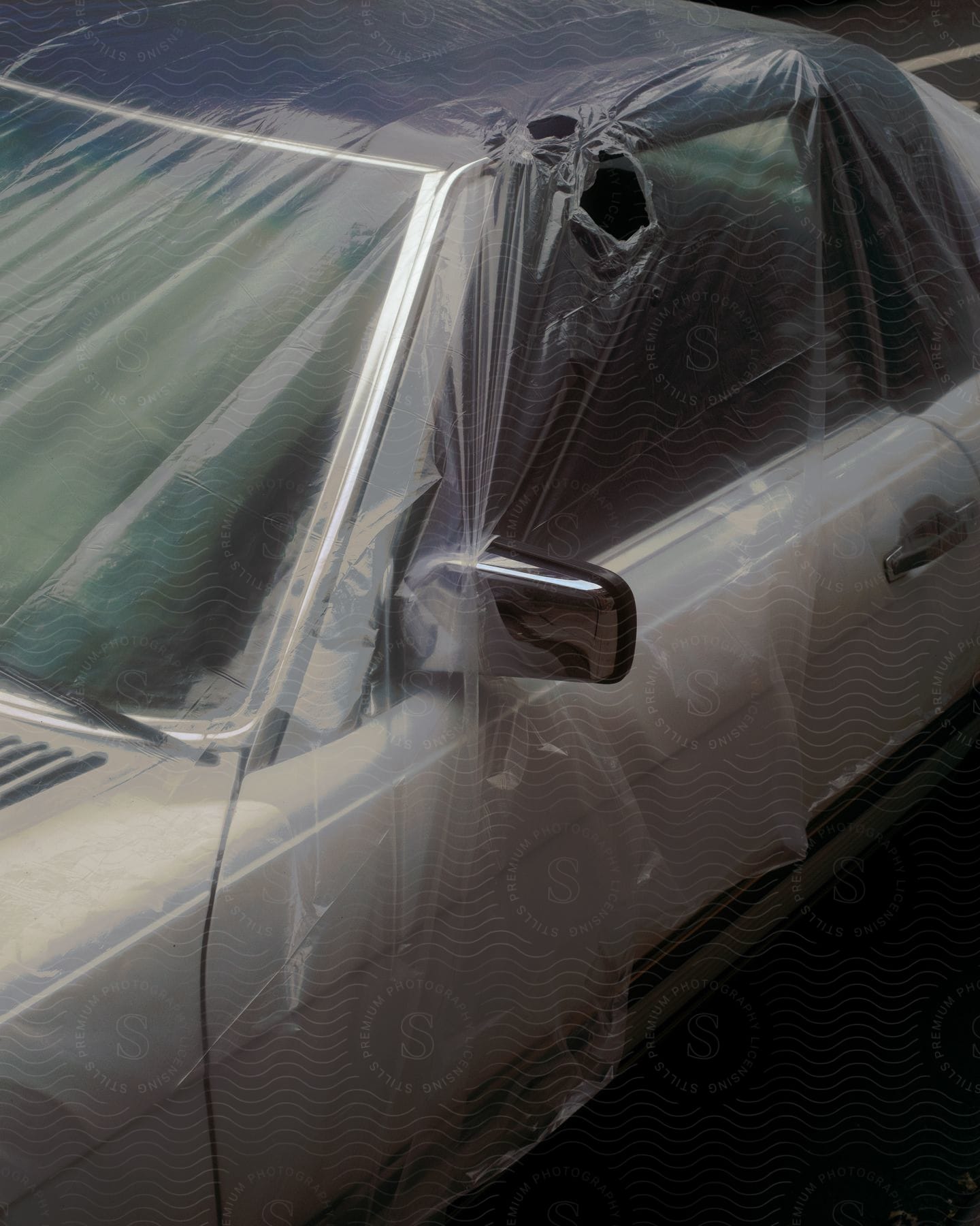 White car wrapped in plastic with holes above the door frame