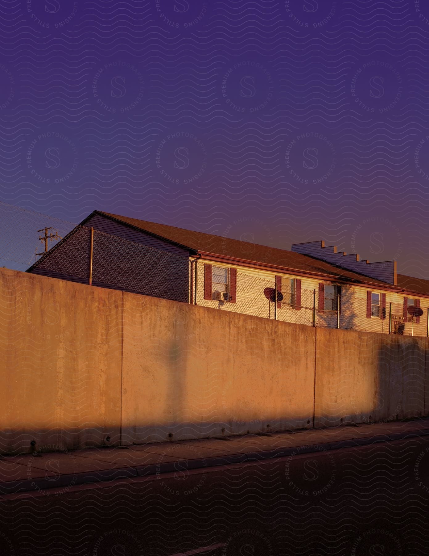 A building by the roadside with a fence running alongside it