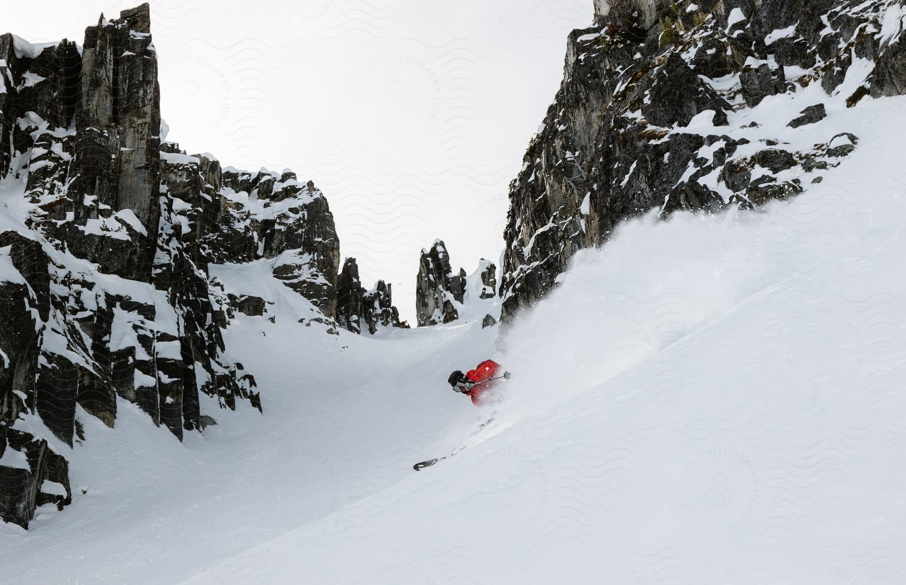 A snowboarder descends a snowcovered mountain with rocky peaks