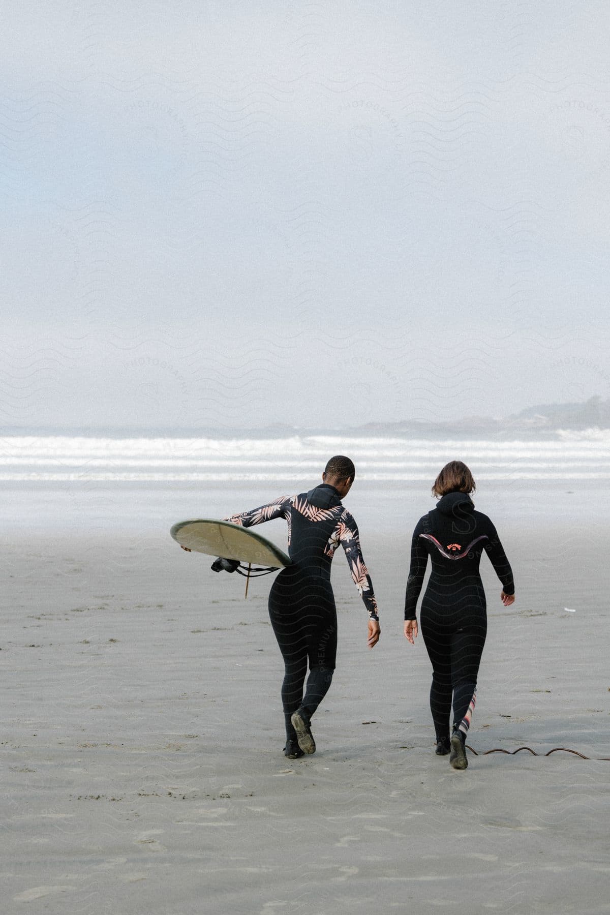 Two people walking on a beach by the sea in tofino british columbia