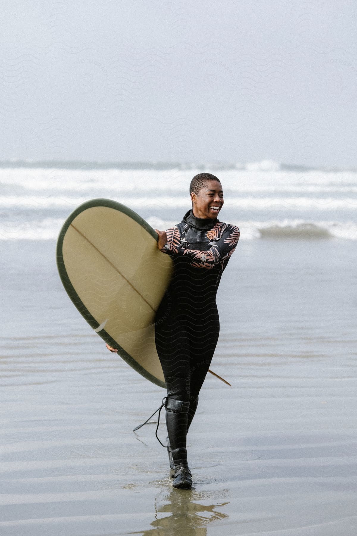 A woman walking with a surfboard out of the ocean